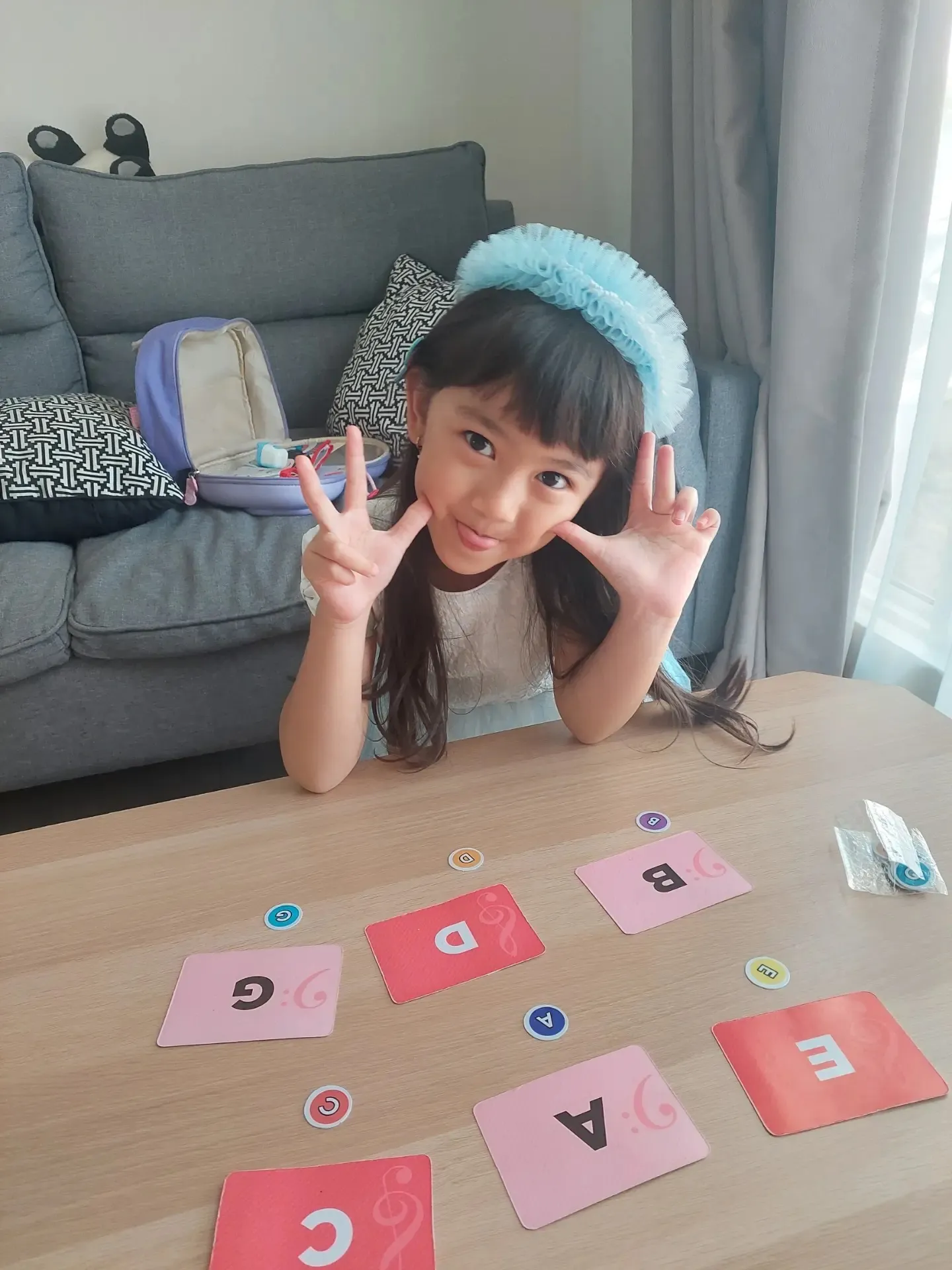 Murid tersenyum di samping kartu huruf not